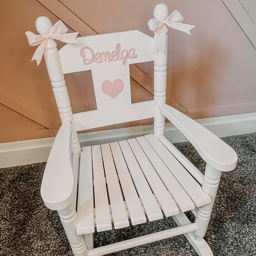 Personalised white wooden children’s rocking chair with decorative name lettering and bow